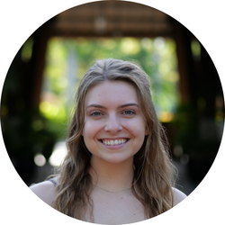 Close-up headshot of tutor Madelyn standing outside in front of a wooden bridge. Greenery out of focus is in the background.