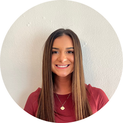 Close-up headshot of tutor Savannah wearing a red shirt and standing in front of a white wall.